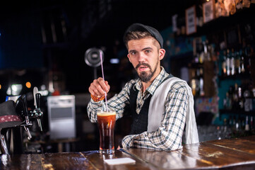 Expert bartender formulates a cocktail while standing near the bar counter in nightclub