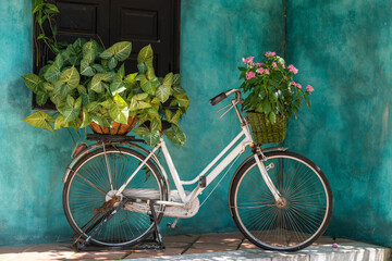 Witte vintage fiets met mand vol bloemen naast een oud gebouw in Danang, Vietnam, close-up