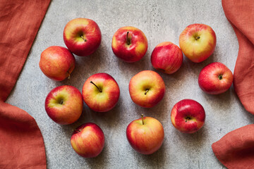 Scattering of fresh ripe red apples in a frame of linen napkins, top view