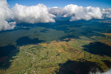 Aerial view from airplane window at high altitude of earth covered with white puffy cumulus clouds