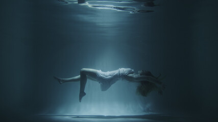 girl in a white dress swims underwater