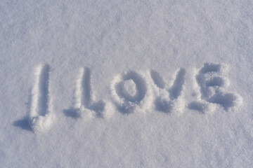 Text I love on a white fresh snow in winter, close up