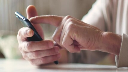 Elderly people are active users of gadgets and the Internet theme. Close up of hand of an elderly man using smartphone clicking on screen while browsing content. Selective focus