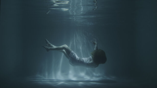 a girl in a white dress falls under the water