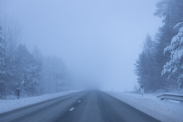 Fototapeta na wymiar Foggy road in the evening. Winter asphalt road blurred. Blurred photo