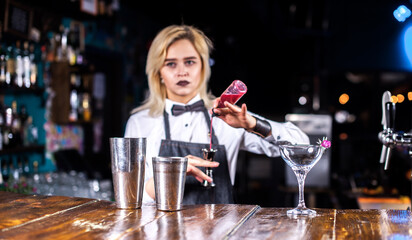 Girl bartender creates a cocktail in the saloon