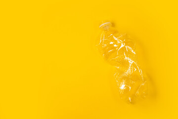One used plastic bottle on a yellow background. Earth Day and envinmental pollution. Top view, copy space. Ecology.