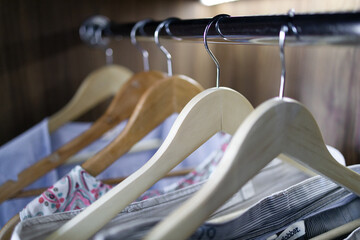 Color clothes hang on clothing rack in a wooden cabinet with lighting in the house