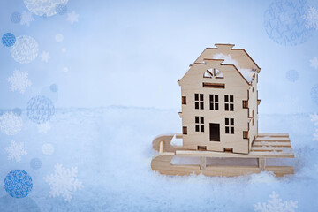 model of a wooden cottage on a sled in winter in the snow, the concept of a warm eco-friendly house...