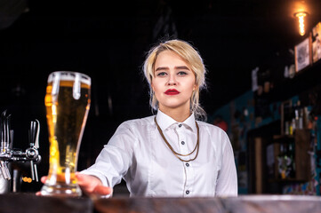 Girl bartender creates a cocktail on the alehouse
