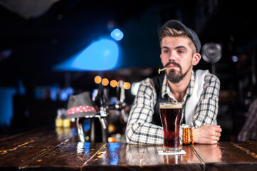 Young tapster decorates colorful concoction at the bar counter