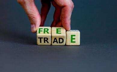 Free trade symbol. Businessman turns wooden cubes and changes the word trade to free. Beautiful grey table, grey background, copy space. Business and free trade concept.
