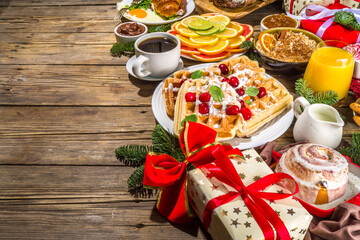 Festive Christmas morning breakfast or brunch table, with traditional foods – pancakes, Belgian waffles, fried eggs, croissant, stolen, cookies, with orange juice and coffee, cinnamon rice porridge 