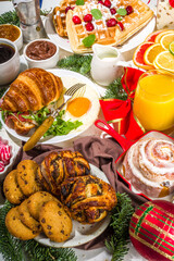 Festive Christmas morning breakfast or brunch table, with traditional foods – pancakes, Belgian waffles, fried eggs, croissant, stolen, cookies, with orange juice and coffee, cinnamon rice porridge 