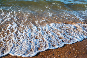 Close up of sea water runs onto the sandy shore.