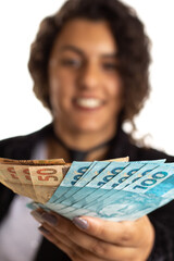 Brazilian woman is dealing with money from Brazil. Person offering money and smiling Isolated on white background.