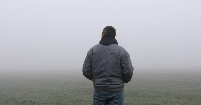 Fog landscape. Man walking alone on scary foggy misty road. 