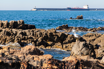 View of the Atlantic Ocean in the city of Porto, Portugal. Blue sky, kaini on the shore, ocean and water splashes.