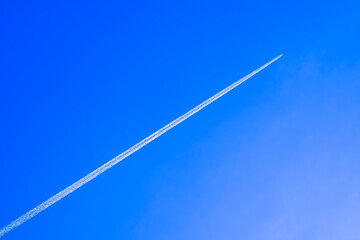 Jet airplane with white contrail on blue sky in morning time