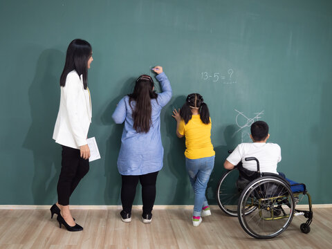 Spacial classroom of kids learning and playing at in the classroom with teacher helping on blackboard background