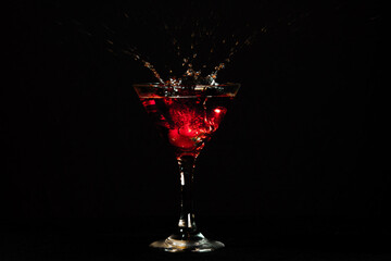 red martini cocktail splashing on black background