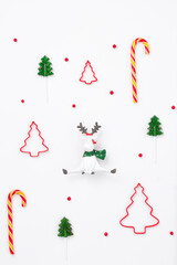 Minimal New Year composition of Christmas reindeer among Christmas trees and red winter berries. New year concept. Gift wrapping pattern 