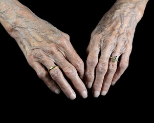 Fototapeta premium Aging process - very old senior woman hands isolated on black background. Hands, wrinkled skin. Life passes.