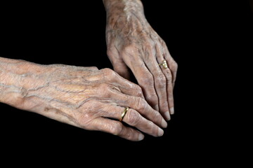 Fototapeta premium Aging process - very old senior woman hands isolated on black background. Hands, wrinkled skin. Life passes.