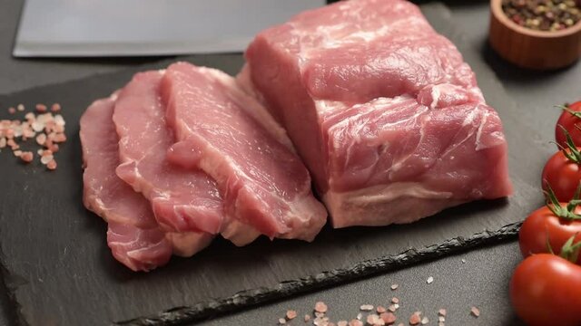 Raw pork steak on a cutting board with herbs and spices