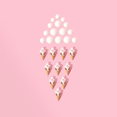 Ice cream cone pattern made of white christmas baubles under direct light on pastel pink background. Christmas and new year celebration concept, flat lay perspective, square ratio.