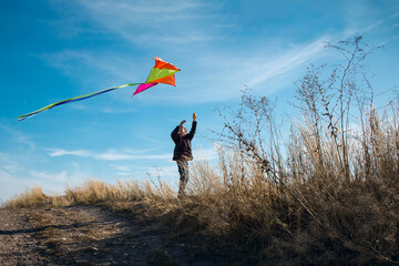 A boy with a kite against the blue sky. Bright sunny day. European appearance boy. Yellow grass