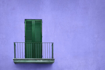 metallic gray balcony with green wooden sash door with shutters on blue violet wall - obrazy, fototapety, plakaty