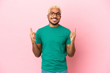 Young Colombian handsome man isolated on pink background pointing up a great idea