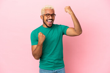 Fototapeta premium Young Colombian handsome man isolated on pink background celebrating a victory