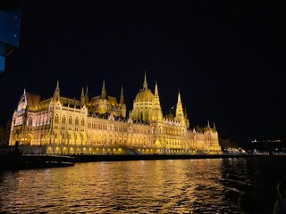 Fototapeta premium Illuminated Parliament building of Budapest at night with dark sky and reflection in Danube river