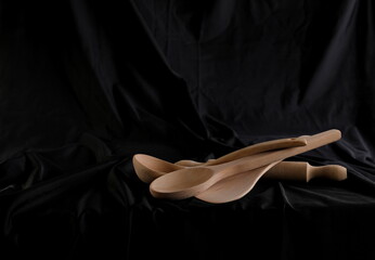 Empty wooden spoons on black luxury fabric table top background and texture
