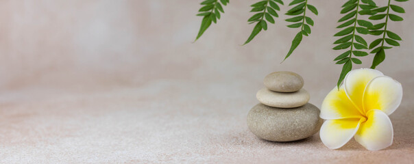 Banier. Piramides van grijze zen pebble meditatie stenen met groene bladeren op beige achtergrond. Concept van harmonie, balans en meditatie, spa, massage, ontspannen.