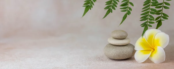 Foto auf Leinwand Banner. Pyramiden aus grauen Zen-Kiesel-Meditationssteinen mit grünen Blättern auf beigem Hintergrund. Konzept der Harmonie, Balance und Meditation, Spa, Massage, Entspannung. © strigana