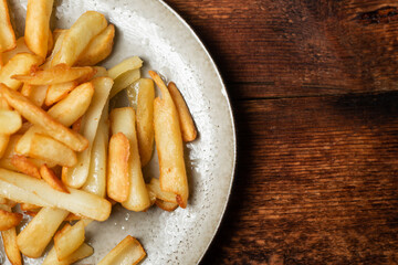 Fried French fries in wedges on a plate on a wooden background.