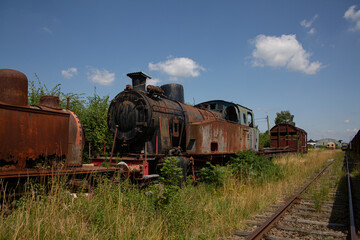 Rusty old steam train next to tracks parked in the grass