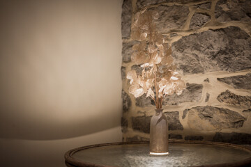 Vase with decorative flowers against rough rock wall