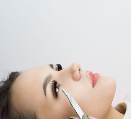 Eyelash Extension Procedure. A woman's eye with long eyelashes. Eyelashes, close-up, macro, selective focus. Tweezers. Beautiful girl on eyelash extension procedure