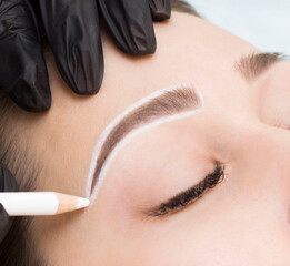 Permanent eyebrow makeup. The master draws a sketch before the permanent makeup procedure with a...