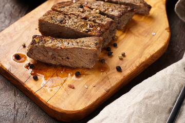 A piece of cooked beef meat steak on wooden board cut in slices
