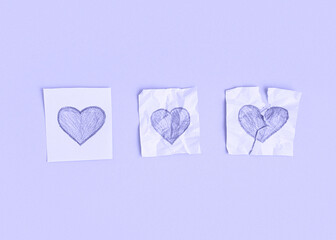 Three hearts drawn on pieces of paper on a very peri background