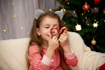 A cute girl holds sweets in the shape of a heart. New year. Home.