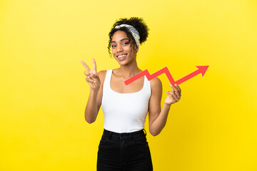 Young african american woman isolated on yellow background holding a catching a rising arrow and celebrating a victory