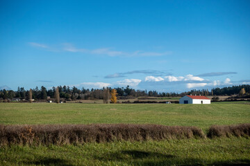 Wide, scenic view of a white barn on a large plot of farm land in the Pacific Northwest