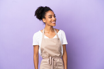Restaurant waiter latin woman isolated on purple background looking side