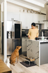 Woman With Dog In Kitchen At Home